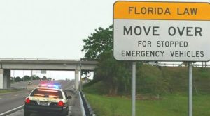 A person learns that Florida's Move Over Law requires drivers to change lanes or slow down when approaching stopped vehicles displaying warning lights on the side of the road, including law enforcement, emergency, sanitation, utility service, tow trucks, and certain disabled vehicles. If a lane change is not possible, drivers must reduce their speed by 20 mph below the posted speed limit or to 5 mph if the speed limit is 20 mph or less. 